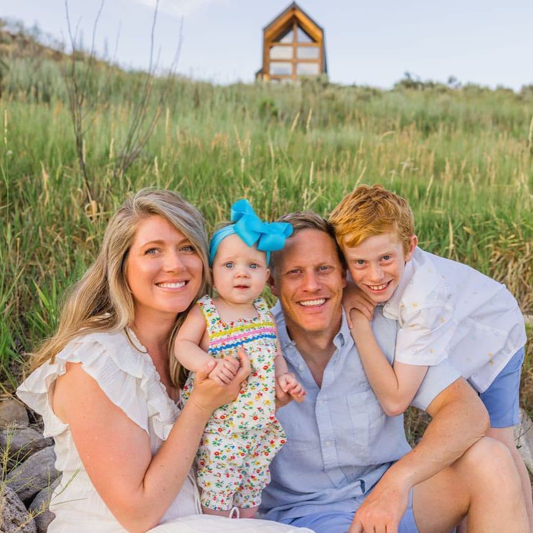 Happy family in a mountain meadow with their home in the background